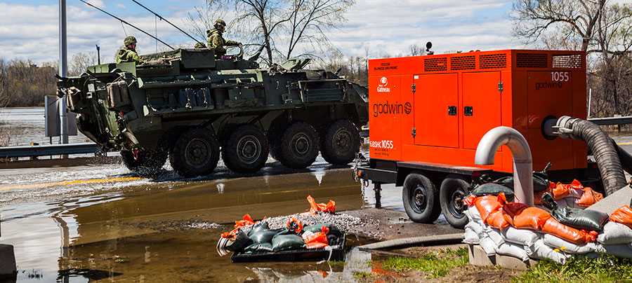 Floodwater being pumped away from a road by a large water pump