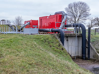 Water pump draining water from a stream to control high water levels and prevent floods