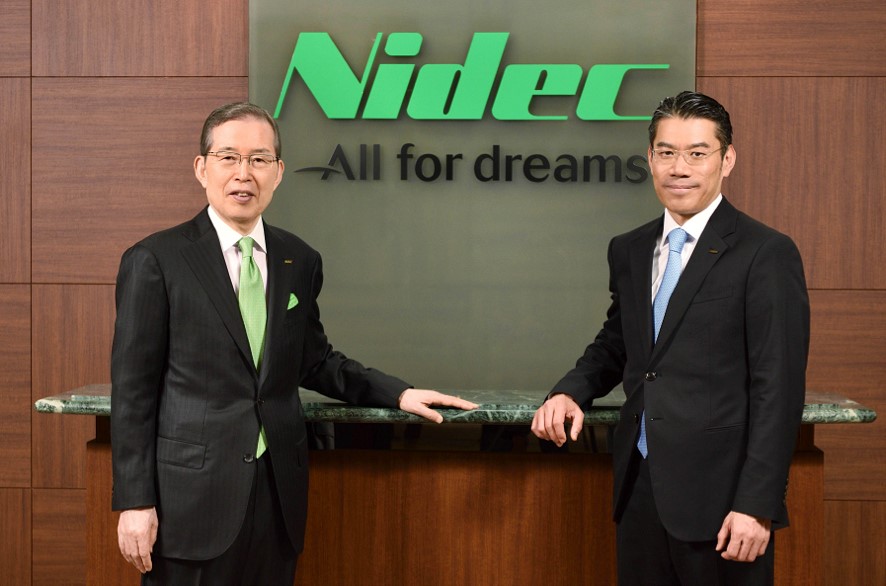 Nidec Corporation Chairman Mr. Nagamori and President Mr. Yoshimoto stand in front of the Nidec logo.
